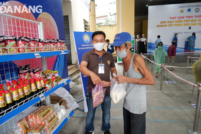 A man receiving 2 out of essential items at the ‘zero-VND Happy supermarket’ after receiving 2kg of rice