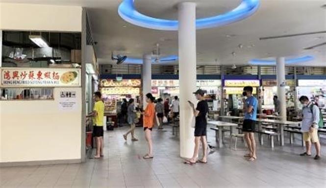  Người dân thực hiện giãn cách xã hội khi xếp hàng mua đồ ăn tại Singapore ngày 11/4/2020. Ảnh: Kyodo/TTXVN