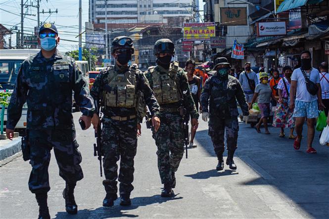  Cảnh sát tuần tra nhắc nhở người dân về các biện pháp phòng tránh dịch COVID-19 tại một chợ ở Manila, Philippines, ngày 21/4. Ảnh: AFP/TTXVN