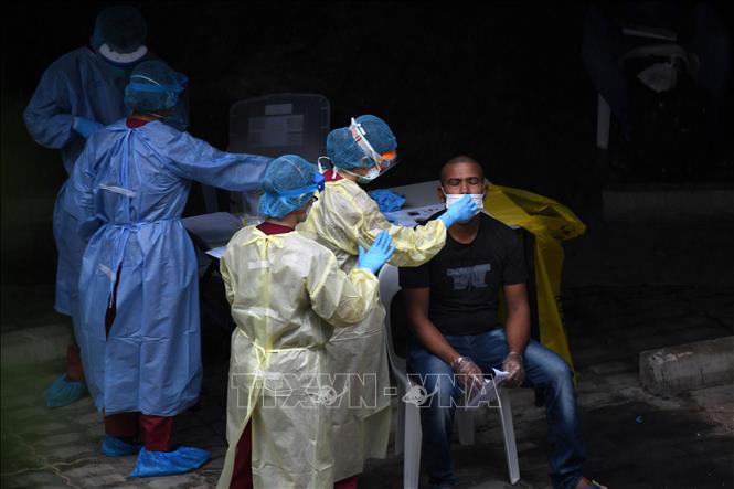 Nhân viên y tế lấy mẫu xét nghiệm Covid-19 cho người lao động nước ngoài tại Singapore ngày 27-4-2020. Ảnh: AFP/TTXVN