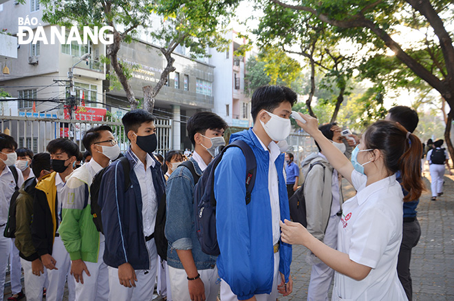 Nhân viên y tế, đoàn thanh niên Trường THPT Phan Châu Trinh đo thân nhiệt cho học sinh trước khi vào lớp. Ảnh: N.P