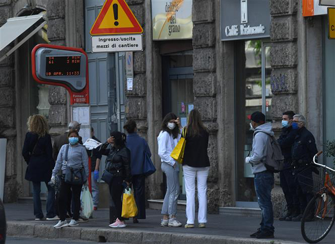 Người dân đợi xe buýt tại bến xe ở Milan, Italy ngày 18-4-2020 trong bối cảnh dịch Covid-19 đang hoành hành. Ảnh: THX/TTXVN