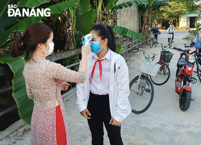 Teachers of the Do Thuc Tinh Junior High School in Hoa Vang District’s Hoa Khuong Commune standing by school gates to ask pupils to have their temperatures checked