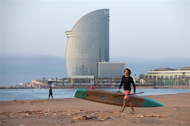 Người dân đi lướt ván tại bãi biển La Barceloneta ở Barcelona, Tây Ban Nha ngày 8/5/2020. Ảnh: AFP/TTXVN