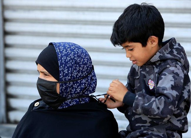 Một cậu bé giúp mẹ đeo khẩu trang ở Sidon, Lebanon.