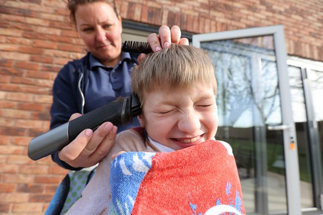 Mẹ tự tay cắt tóc cho cậu bé Zac (8 tuổi) ở Keele, Anh.