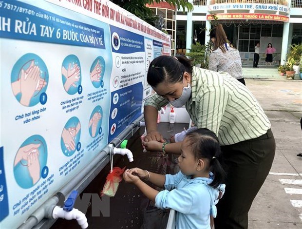 A teacher guides a student how to wash hands correctly (Source: VNA)