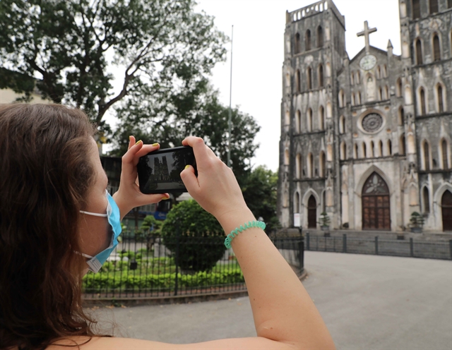 A tourist takes a photo of St Joseph's Cathedral in Ha Noi after the social distancing regulations were eased