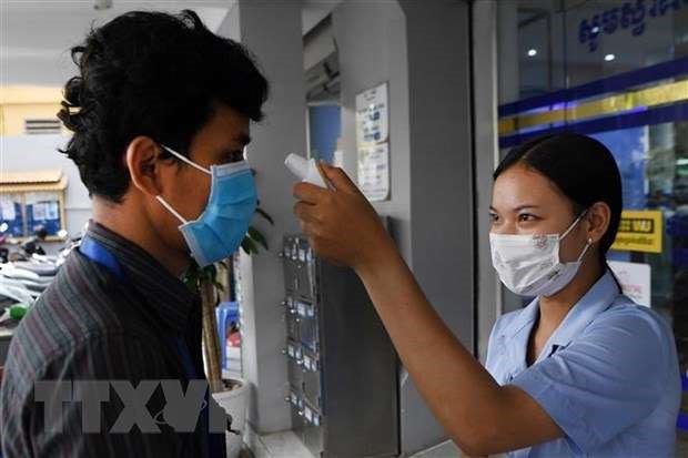 Checking temperature for a customer at a bank in Cambodia (Photo: AFP/VNA)