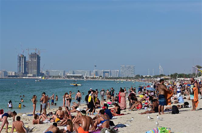 Người dân tắm nắng trên bãi biển ở Dubai, UAE, ngày 13-3-2020. Ảnh: AFP/TTXVN