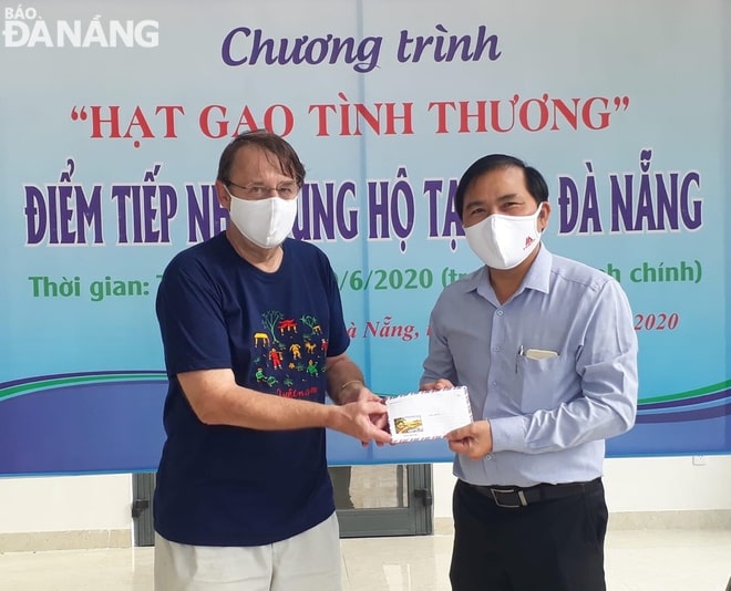 Mr Demaseure Thierry (left) donating 5 million VND in cash to Da Nang Newspaper Editor-in-chief Nguyen Duc Nam to support the operation of rice dispensers.