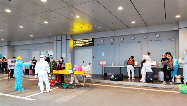 Health workers at Van Don International Airport instruct people who returned home from Russia on May 13.