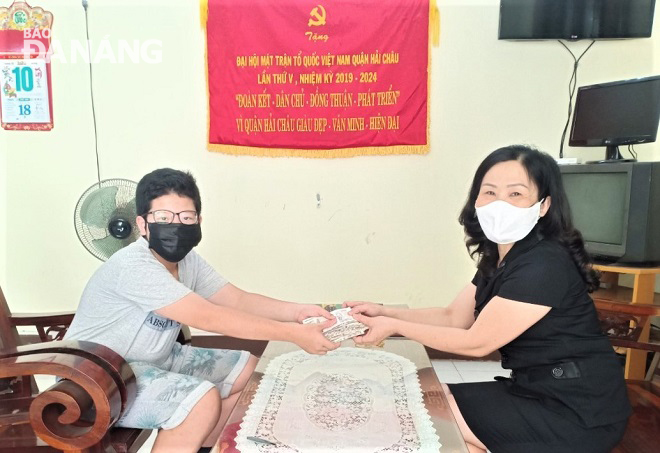 Phó Chủ tịch Ủy ban MTTQ Việt Nam quận Hải Châu Trần Thị Cúc Hương (bìa phải) tiếp nhận ủng hộ từ em Hồ Kinh Nam Khoa.  Ảnh: LAM PHƯƠNG
