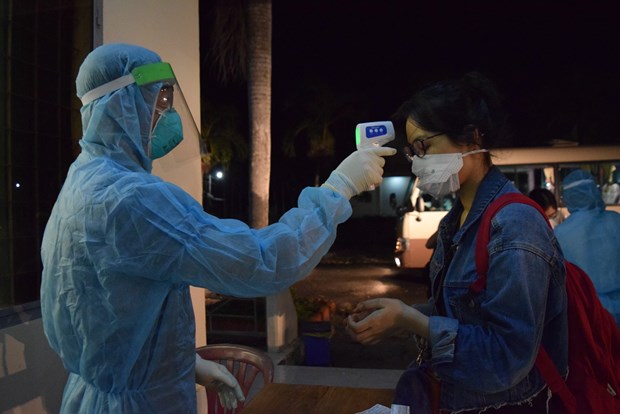 A health worker at Can Tho Airport checks the body temperature of a Vietnamese repatriated from the Philippines on May 14 (Photo: VNA)