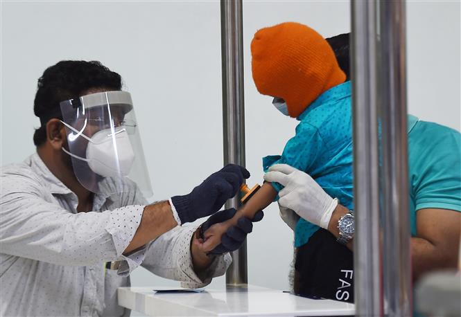 Nhân viên y tế đóng dấu kiểm dịch cho người dân trở về từ Dubai tại sân bay ở Chennai, Ấn Độ ngày 9/5/2020. Ảnh: THX/ TTXVN
