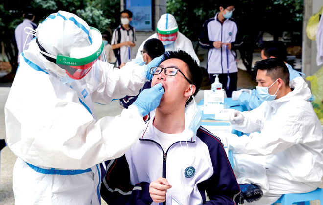 Học sinh THPT ở thành phố Vũ Hán (Trung Quốc) được xét nghiệm Covid-19 trước khi trở lại trường hồi đầu tháng 5. Các ca mắc Covid-19 đầu tiên được phát hiện ở Vũ Hán, sau đó lan ra các tỉnh, thành khác của Trung Quốc và thế giới. Ảnh: Reuters