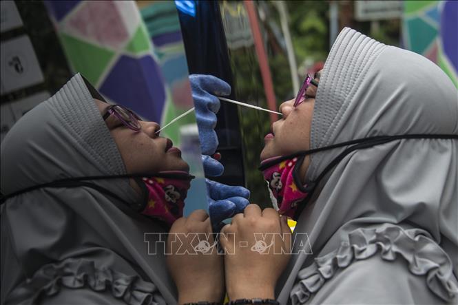 Nhân viên y tế lấy mẫu xét nghiệm Covid-19 cho người dân ở Surabaya, Indonesia ngày 20-5. Ảnh: AFP-TTXVN