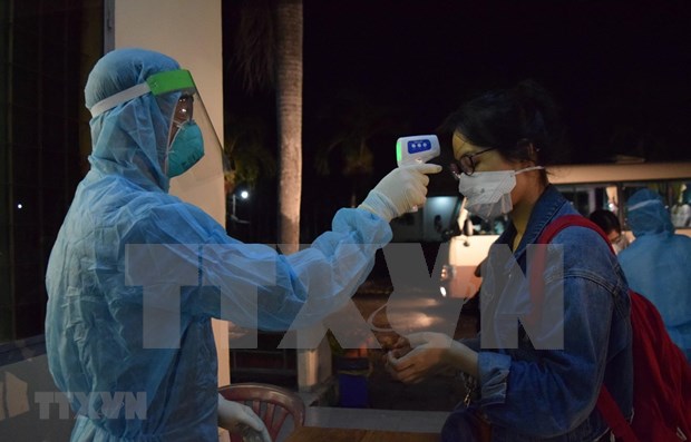 A medical worker checks temperature of a Vietnamese returnee from the Philippines. (Photo: VNA)