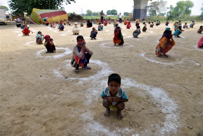 Trẻ em thực hiện giãn cách xã hội phòng lây nhiễm COVID-19 khi xếp hàng chờ nhận bữa ăn miễn phí tại East Delhi, Ấn Độ ngày 11/5/2020. Ảnh: THX/TTXVN