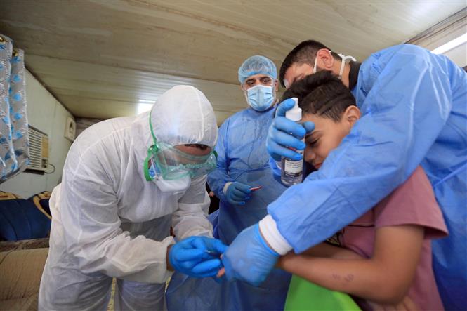 Nhân viên y tế lấy mẫu xét nghiệm COVID-19 cho một em nhỏ tại Baghdad, Iraq ngày 21/5/2020. Ảnh: THX/TTXVN