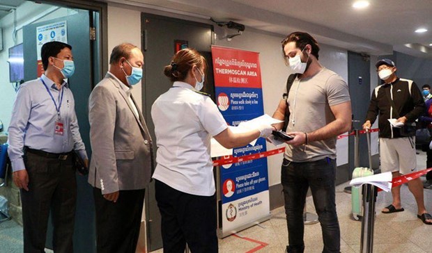 A health official checks documents from an arriving passenger at the Phnom Penh international airport. (Photo: https://www.khmertimeskh.com/)