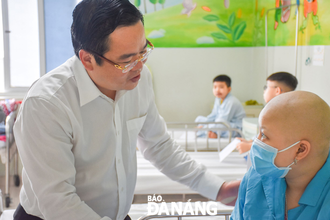 Vice Chairman Trung (left) speaking to a child patient at the city’s Cancer Hospital