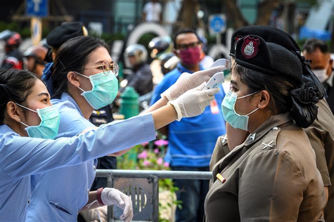  Nhân viên y tế kiểm tra thân nhiệt cho cảnh sát ở Bangkok, Thái Lan. Ảnh: AFP/TTXVN