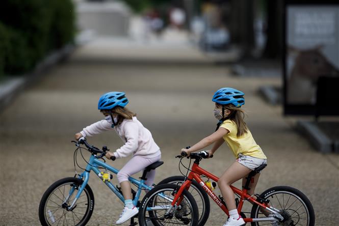  Trẻ em đạp xe trên phố ở Washington D.C, Mỹ trong bối cảnh dịch COVID-19 lây lan ngày 18/5/2020. Ảnh: THX/TTXVN