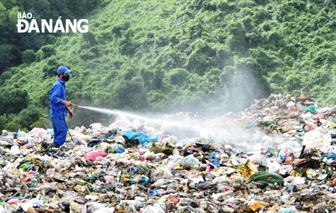 A worker from the city’s Waste Management and Treatment Factory using odor-reducing sprays in the Khanh Son Landfill