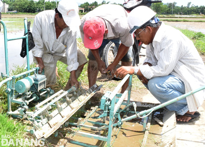 Các hộ nông dân đang tìm hiểu cấu tạo, nguyên lý hoạt động và vận hành máy cấy lúa hữu cơ loại kéo bằng tay. Ảnh: HOÀNG HIỆP