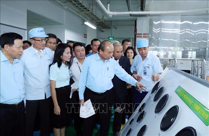 Thủ tướng Nguyễn Xuân Phúc xem các sản phẩm của Công ty TNHH Điện tử Foster (Việt Nam). Ảnh: Thống Nhất/TTXVN