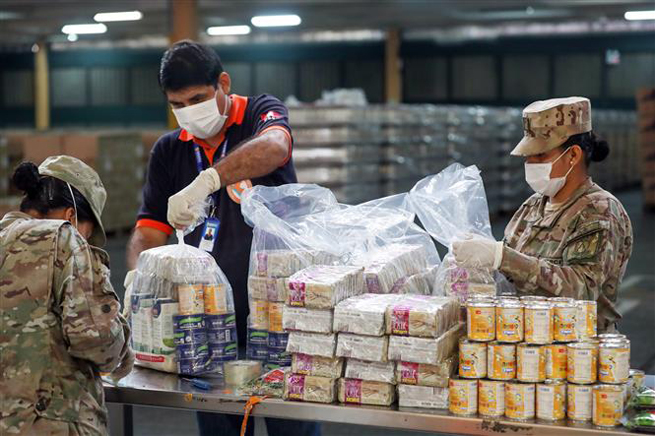 Lực lượng phòng vệ và dân sự Peru đóng gói lương thực cứu trợ cho người dân gặp khó khăn do ảnh hưởng của dịch Covid-19 tại Lima ngày 28-5-2020. Ảnh: AFP/TTXVN
