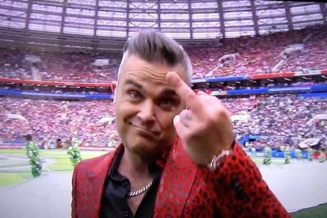 Biểu tượng “ngón tay thối” trên Windows 10 (ảnh trên) và Robbie Williams bị chỉ trích vì giơ “ngón tay thối” ở khai mạc World Cup 2018. (Ảnh cắt từ clip)