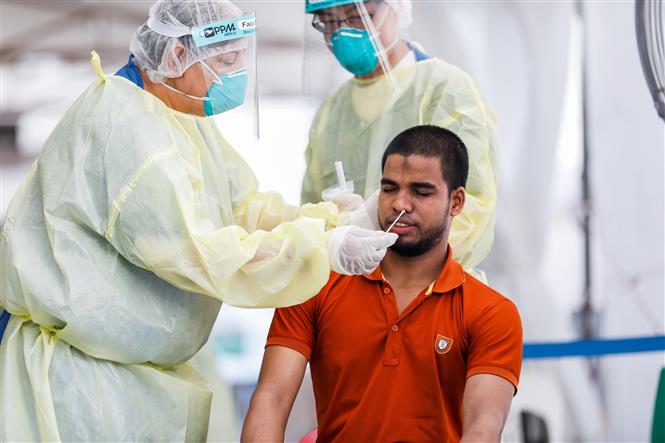 Nhân viên y tế lấy mẫu dịch xét nghiệm COVID-19 cho người dân tại Singapore ngày 15/5/2020. Ảnh: AFP/ TTXVN