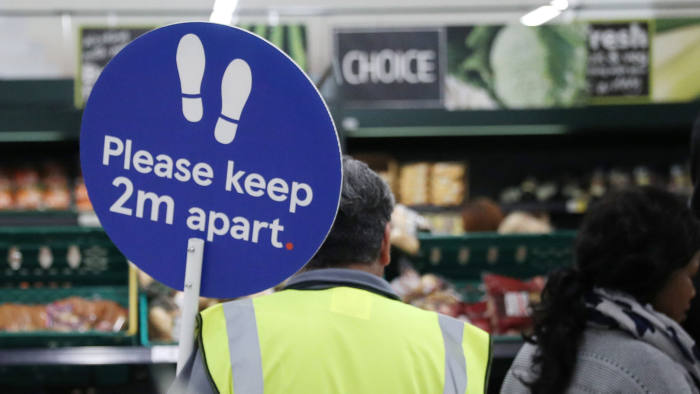 Biển báo yêu cầu tuân thủ giãn cách xã hội trong một siêu thị ở Anh. Ảnh: Financial Times