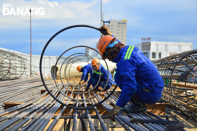 Some construction workers are working at the site of the traffic re-arrangement at the western end of the Tran Thi Ly Bridge in Da Nang in the heat.