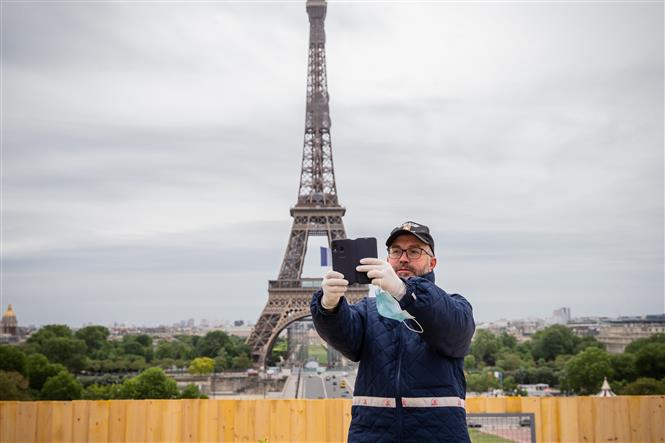  Khách du lịch chụp ảnh lưu niệm trước Tháp Eiffel ở thủ đô Paris, Pháp ngày 11/5/2020. Ảnh: THX/TTXVN