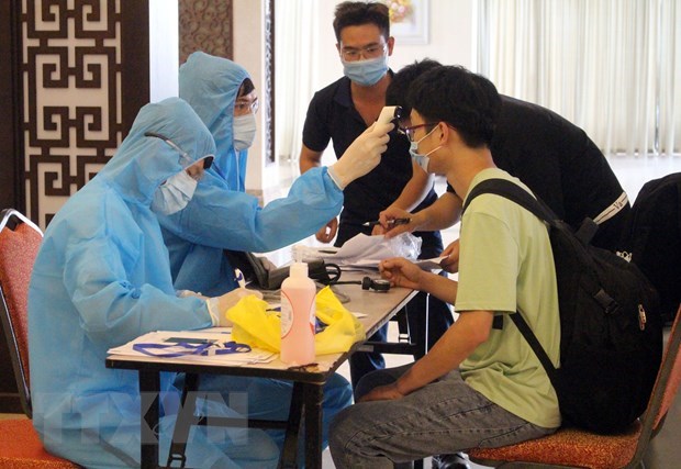 Foreign workers are examined and make health declarations before entering a quarantine facility (Photo: VNA)