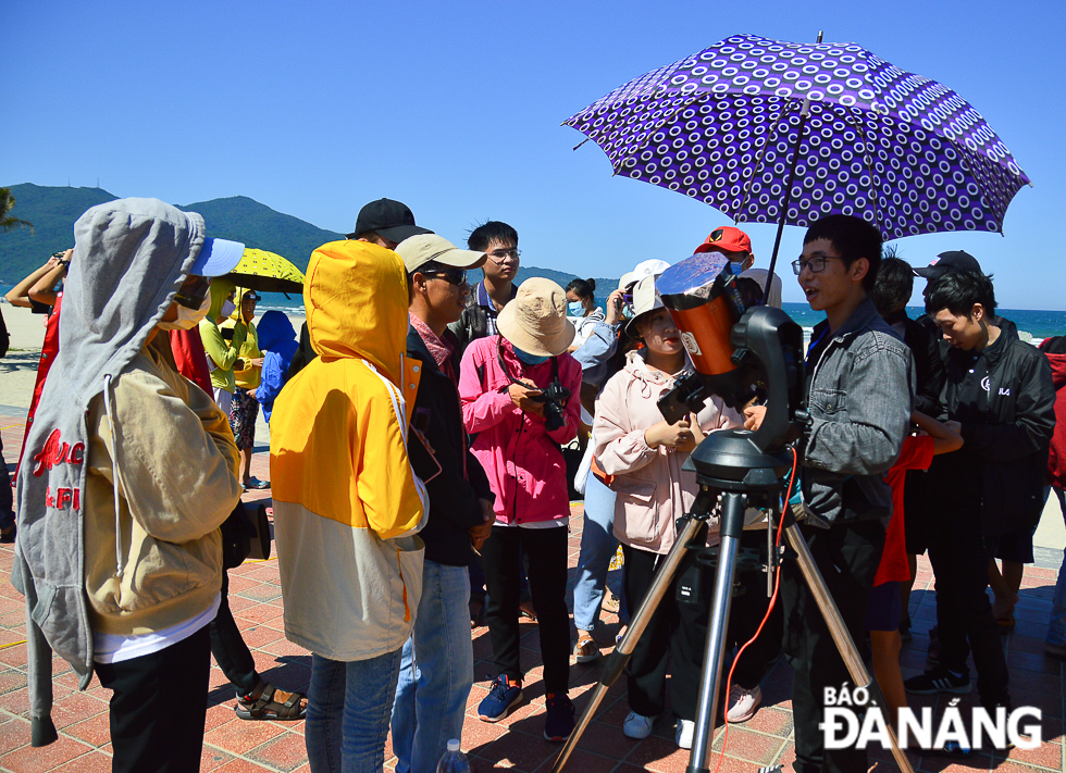 Many people watching the annular eclipse through a telescope with a solar filter 