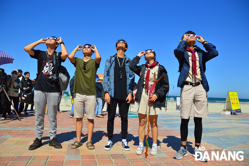 A group of young people using special glasses to watch the eclipse