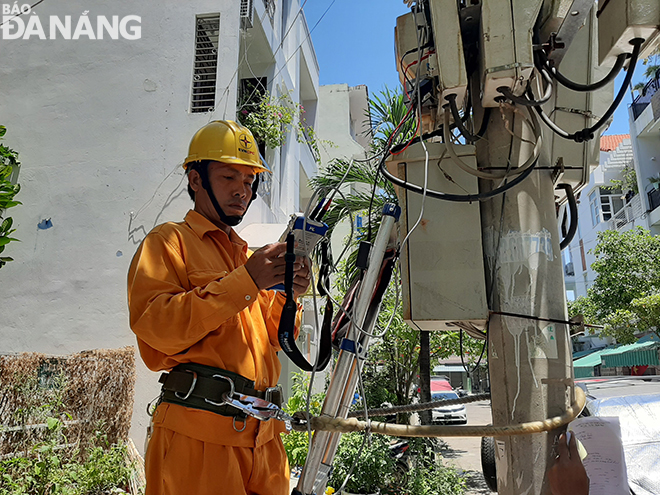 Nhân viên Công ty TNHH MTV Điện lực Đà Nẵng đang kiểm tra chỉ số công tơ của hộ dân. Ảnh: KHÁNH HÒA