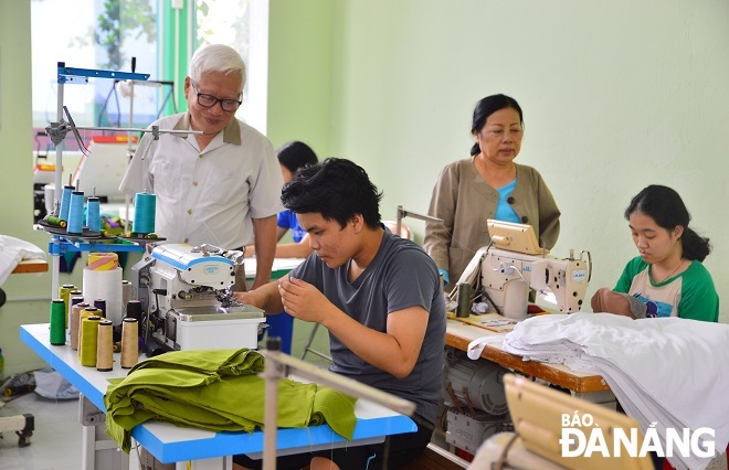 Chairman of the Association Nguyen Hoang Long, (standing, left) at the Lien Chieu District-based sewing facility