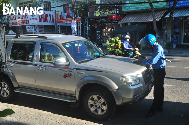 Thanh tra giao thông ghi giấy phạt xe dừng, đỗ sai quy định trên tuyến đường Phan Đăng Lưu. Ảnh: PHƯƠNG UYÊN