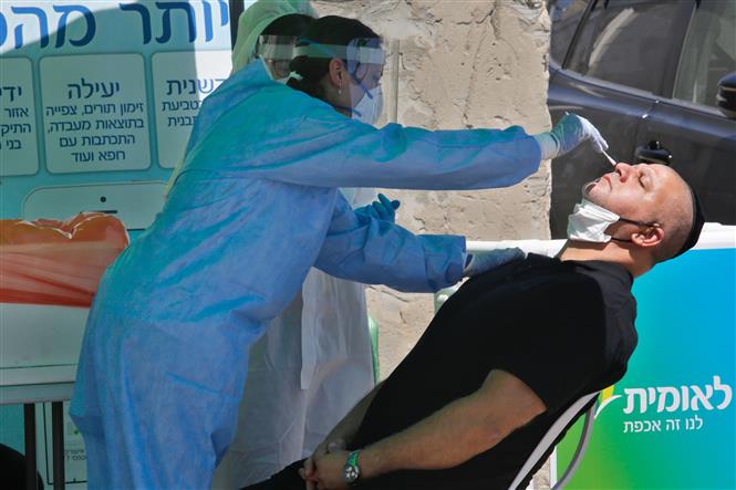  Nhân viên y tế lấy mẫu dịch xét nghiệm COVID-19 cho người dân tại thành phố Lod, Israel ngày 2/7/2020. Ảnh: THX/TTXVN