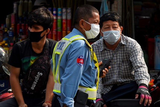 A policeman (C) and people wear facemasks, used as a preventive measure against the COVID-19 novel coronavirus, at a market in Phnom Penh in March this year. (Photo: AFP)