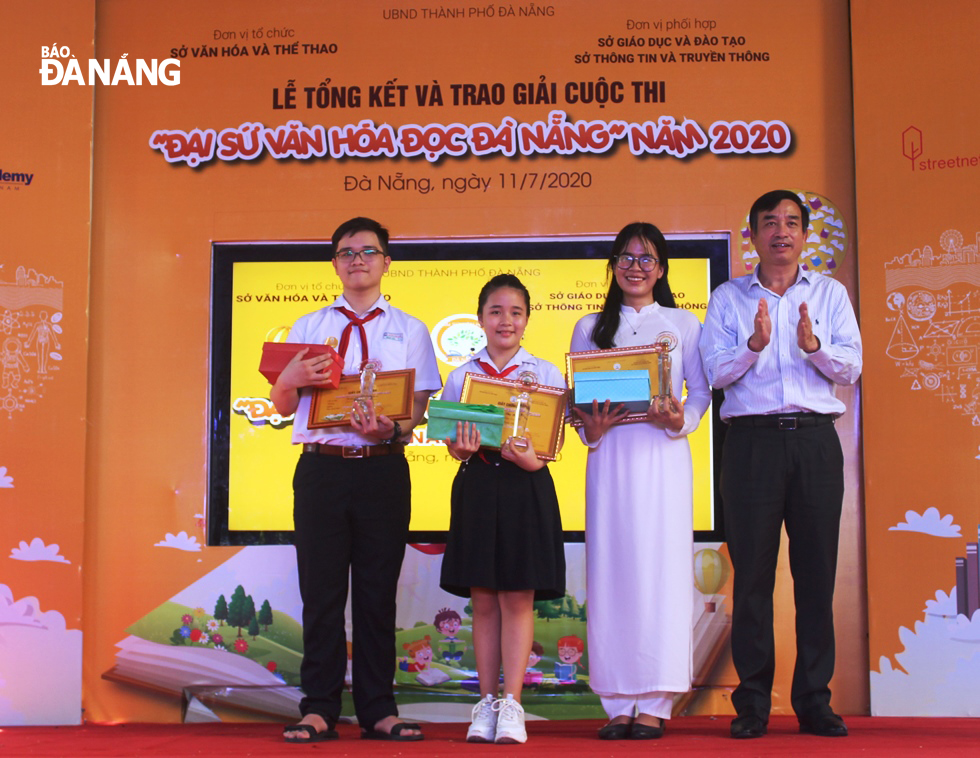 Phó Chủ tịch UBND thành phố Lê Trung Chinh (phải) trao giải cho 3 thí sinh đạt giải thưởng “Đại sứ Văn hóa đọc tiêu biểu”. Ảnh XUÂN DŨNG