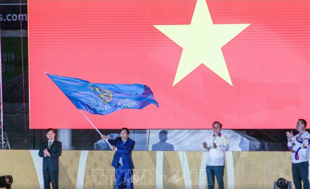 Minister of Culture, Sports and Tourism Nguyen Ngoc Thien takes the flag that marks Vietnam as the host of SEA Games 31 (Photo: VNA)