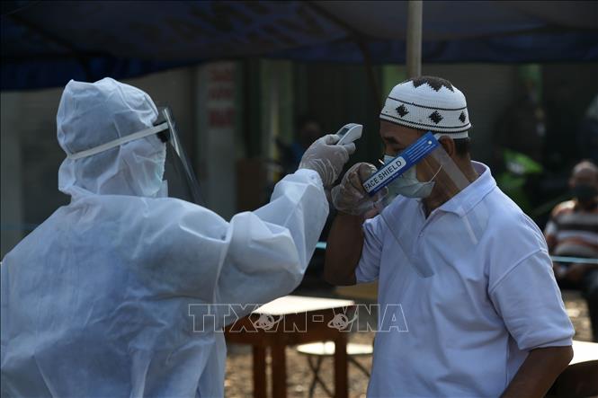 Nhân viên y tế đo thân nhiệt phòng lây nhiễm COVID-19 tại Jakarta, Indonesia ngày 25/6. Ảnh: THX/TTXVN