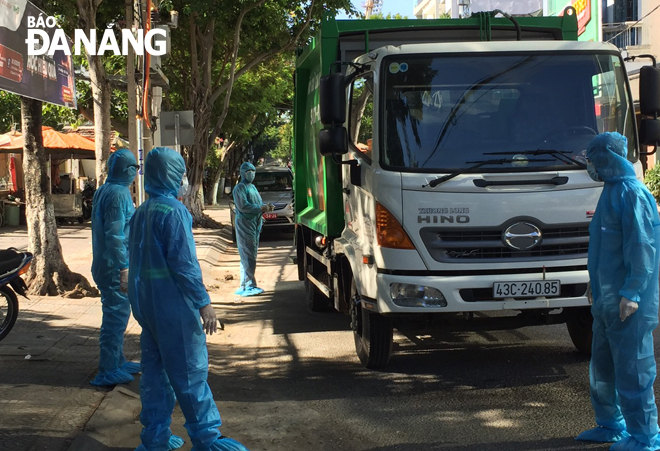 Công ty CP Môi trường đô thị Đà Nẵng đã đưa một xe mới với các công nhân mặc trang phục bảo hộ vào thu gom rác ở khu vực dân cư lân cận 3 bệnh viện đang cách ly y tế vào sáng 28-7.  Ảnh: H.H