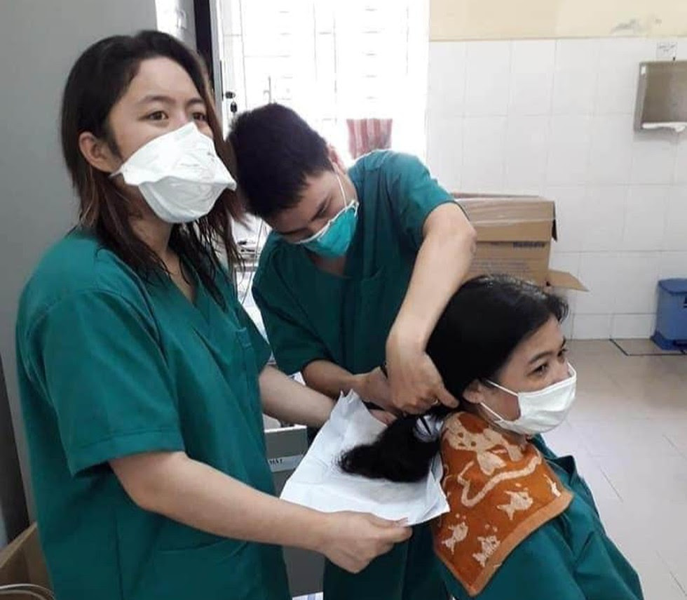 A female medical worker at Da Nang Lung Hospital having her long hair cut 
